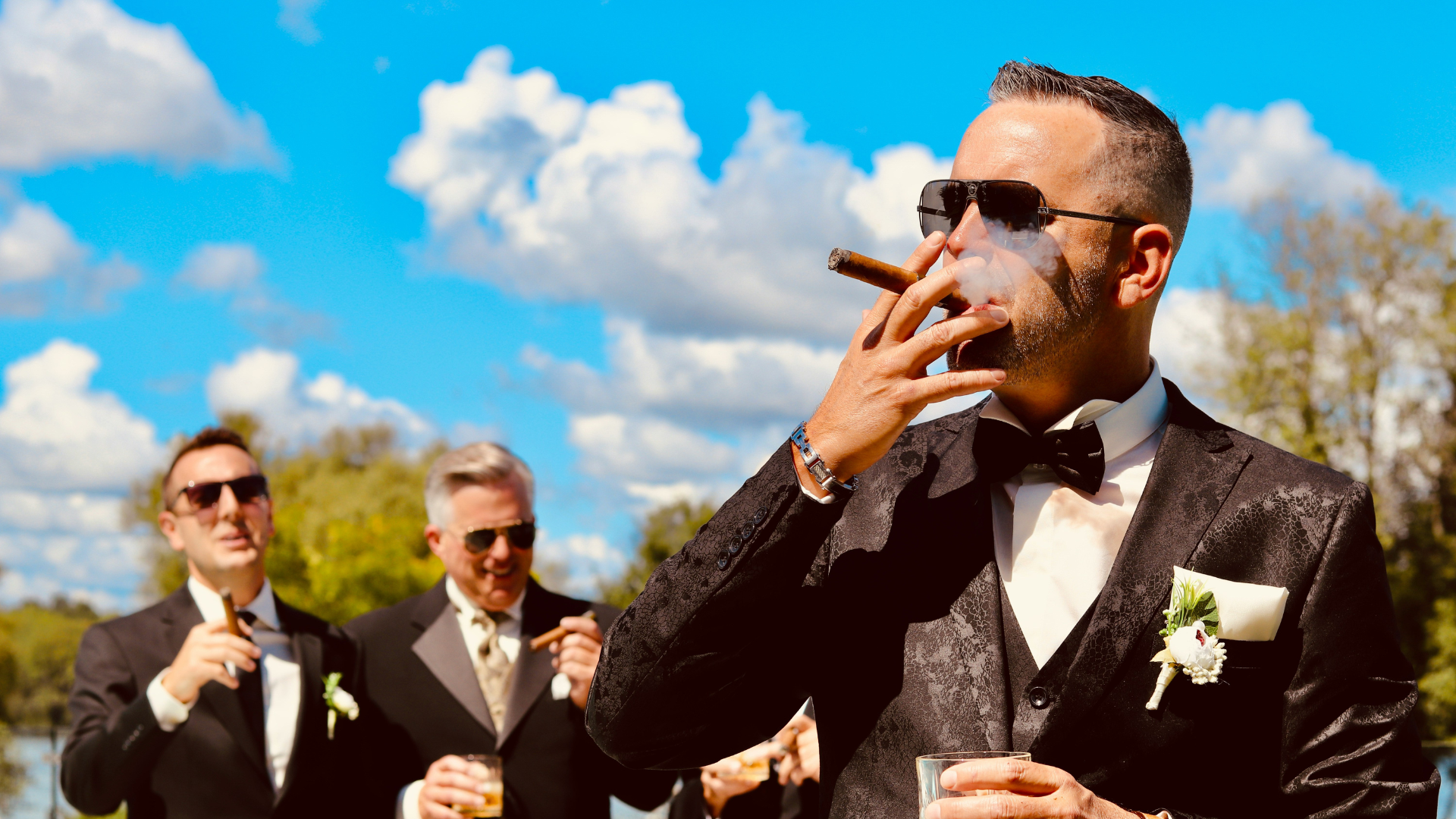 Group of friends enjoying cigars together on a terrace at sunset